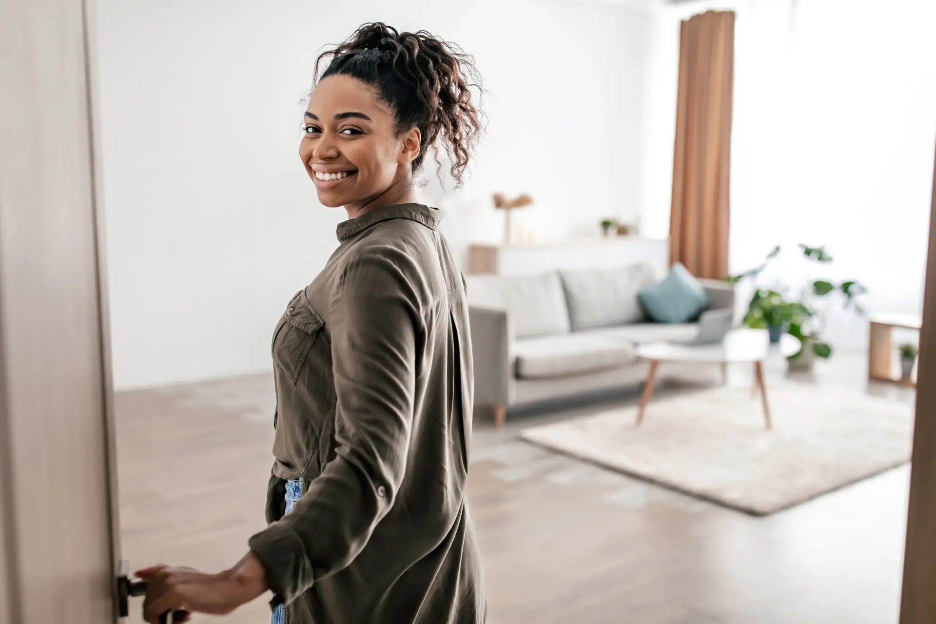 Woman opening door entering apartment with relief and optimism