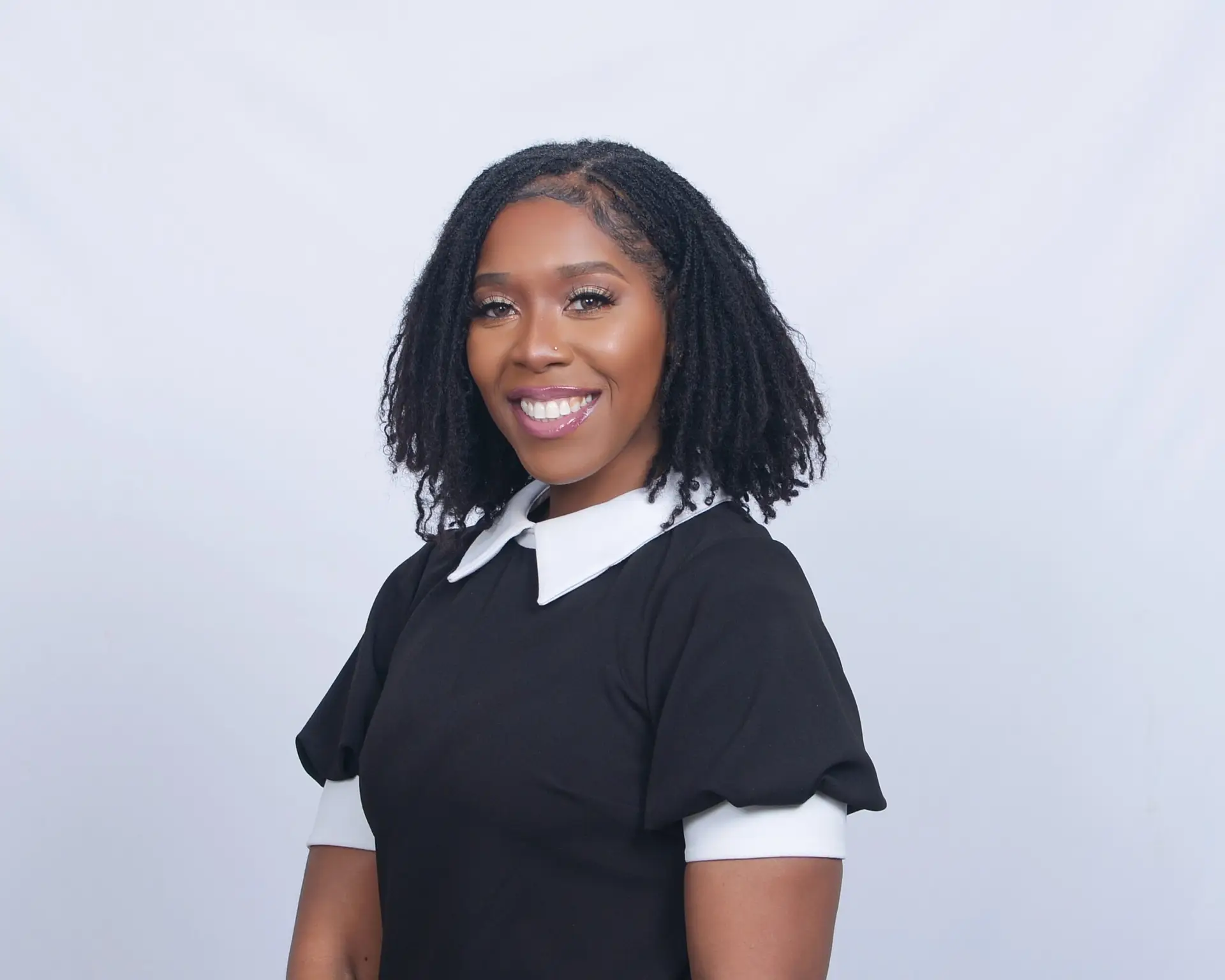 Anita Taylor in a poised professional portrait, wearing a black dress with a white collar, smiling with confidence.