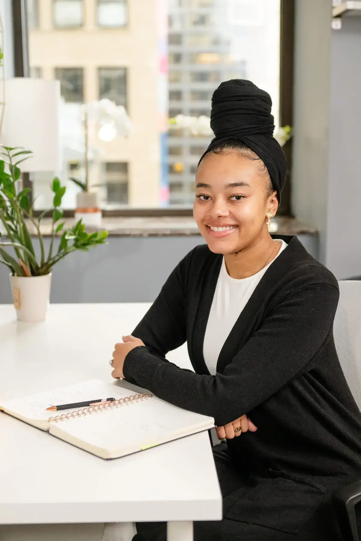 A professional headshot of an intern therapist, a confident and approachable individual with a warm smile, wearing business attire. The background features a modern office setting with natural lighting.