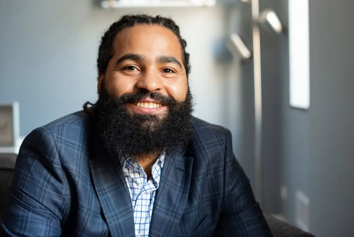 Khoury Daher, licensed therapist at JL Family Services, smiling while seated in a modern office setting.