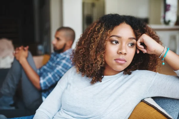Unhappy couple and sad woman upset after argument or conflict with her man on home sofa. Angry girlfriend or female thinking about disagreement or ignoring partner, tired of relationship problems. Couple with Communication issues