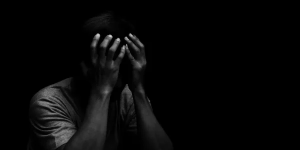 Man sitting alone felling sad worry or fear and hands up on head Man sitting alone felling sad worry or fear and hands up on head on black background
